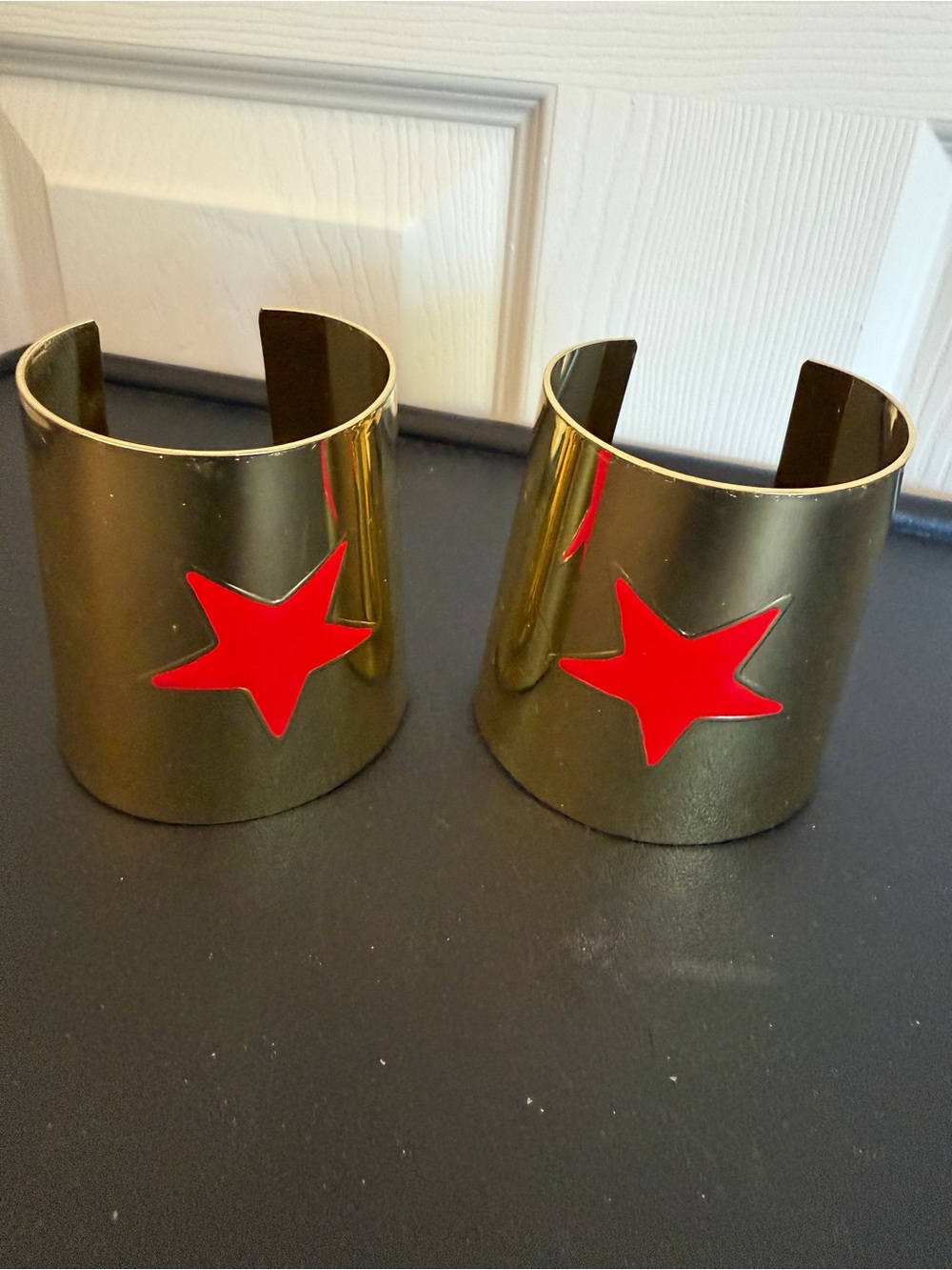 DC Comics Wonder Woman Cuff Set. Gold tone metal bracelets. Red star emblem